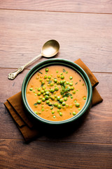 Green Peas curry / Matar masala served in a bowl over moody background. selective focus