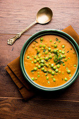 Green Peas curry / Matar masala served in a bowl over moody background. selective focus