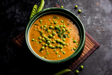 Green Peas curry / Matar masala served in a bowl over moody background. selective focus