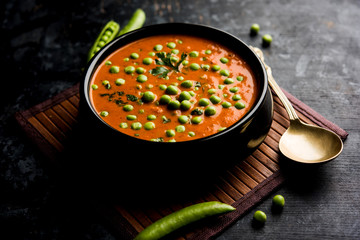 Green Peas curry / Matar masala served in a bowl over moody background. selective focus