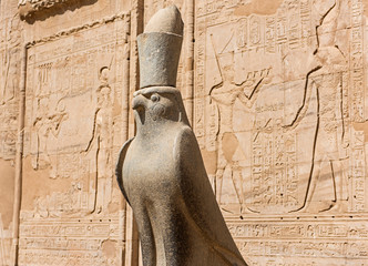 Hieroglyphic carvings on an ancient egyptian temple wall with statue