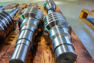 The worm shaft after machining lies on a wooden rack and is ready for use in mechanical engineering and metallurgy.