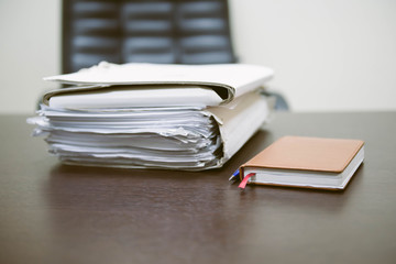 Notepad with ballpoint pen. Pile of unfinished documents on office desk, Stack of business paper. A...