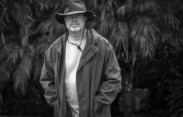 Fototapeta na wymiar Black and white portrait of a man in hat standing in yard