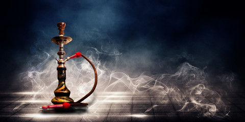 Smoking a hookah on a dark concrete field, in clouds of smoke and neon light