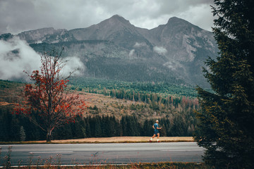 Athlete run under big mountains in autumn. Sport photo, rainy dark mood. Running in nature. Inspirational photo