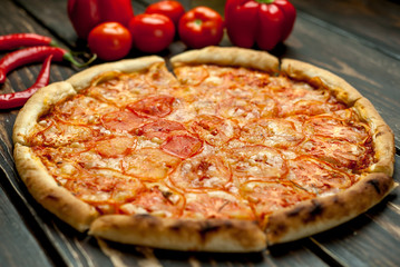 pizza on a wooden table with ingredients, tomato, pepper, sunflower oil