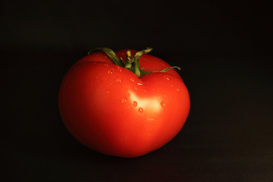 Red tomato isolated on black background. Image contains copy space