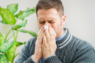 Handsome unshaved man blowing nose to napkin.