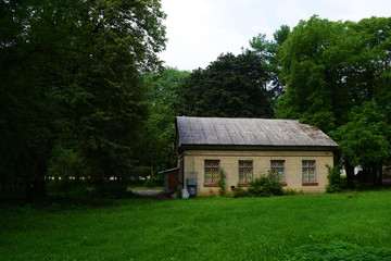 Fototapeta na wymiar View through a green field on a brick house near the trees.