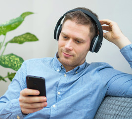 Man using mobile phone with wireless headphones.
