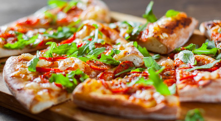 slices vegetarian Pizza with Mozzarella cheese, Tomatoes, pepper, Spices and Fresh arugula. Italian pizza. Pizza Margherita or Margarita on wooden table background