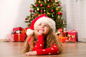 Portrait of cute happy nine year old girl wearing red christmas sweater with many presents, Decorated Christmas tree with stack of wrapped gifts on background. Close up, copy space.