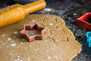 Cooking Christmas gingerbread cookies with rolling pin on a dark background