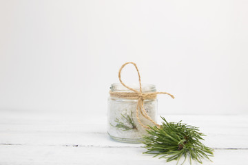 Fototapeta na wymiar Natural herbal sea salt with aromatic fir - perfect for relaxation. Cosmetic jars and bottles with salt, lavender flowers