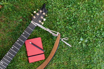 Notebook and pen lying near guitar