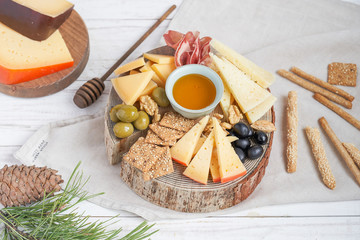 Different kinds of cheese with wine, figs, walnuts, ham, grapes, honey, toast. In a rustic style.