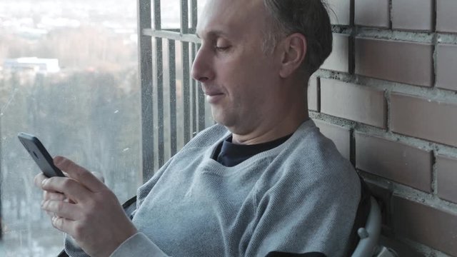 A middle aged man looks at photos on a smartphone and smiles. Nice memories