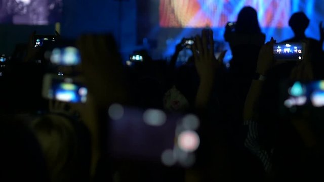 Rock concert bokeh. People dancing with mobile phones. Many Light.