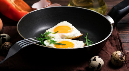 Fried eggs on a skillet on a wooden background
