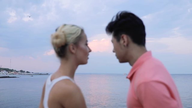 Young couple embracing each other looking at evening calm sea