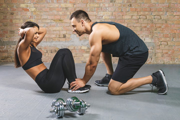 Fitness, sport, training, gym and lifestyle concept - woman with personal trainer doing sit ups in...
