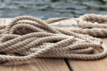 Fototapeta na wymiar nautical rope close up on a wooden dock at waters edge