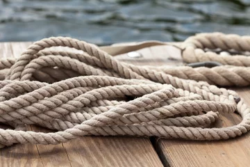 Fotobehang nautical rope close up on a wooden dock at waters edge © Sunnydays
