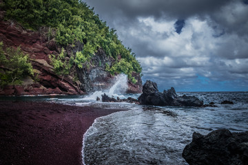 Red sand, mountain crashing waves and stormy sky