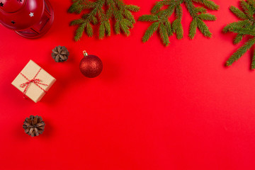 Christmas composition. Fir tree branches, pine cones Christmas decorations and present gift boxes on red background