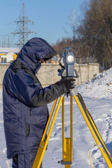 Surveyor mounts gauge for topographic cadastre survey at a construction site in winter