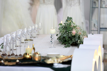 Świeca, bukiet i kieliszki na stole weselnym.