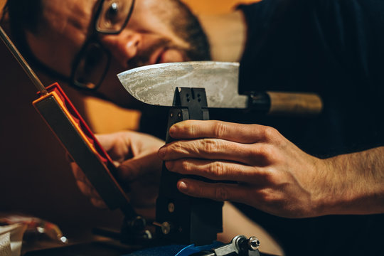 Mann schärft ein japanisches Küchenmesser an einem modernen Schleifwerkzeug