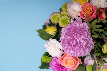 beautiful floral arrangement, pink and yellow rose, pink eustoma, green and pink chrysanthemum, white carnation, pink dahlia on a blue, turquoise background with space for text.