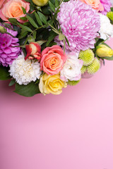 beautiful floral arrangement in the box, pink and yellow rose, pink eustoma, green and pink chrysanthemum, white carnation, pink dahlia on pink background with space for text.