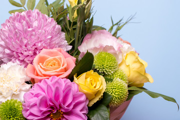 beautiful floral arrangement, pink and yellow rose, pink eustoma, green and pink chrysanthemum, white carnation, pink dahlia on a blue, turquoise background with space for text.