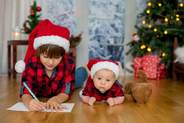 Fototapeta na wymiar Cute newborn and his older brother, writing letter to Santa Claus