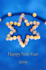 New Year greeting card 2019 with a golden illuminated star in the back