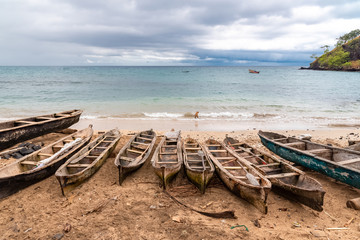 Sao Tome, traditional wooden dugouts on the beach in a fishermen's village, a dog in the sea 