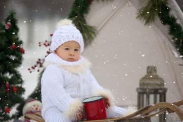 Happy family with kids, having fun outdoor in the snow on Christmas, playing with sledge