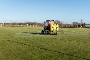 the tractor with fertilizer sprays football playing field