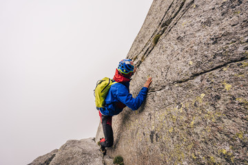 A solo climber ascending a steep rock face. Dangerous climb in a big wall without rope or protection. Free solo.
