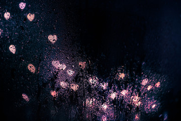 glare of the night city through the window in the drops of rain