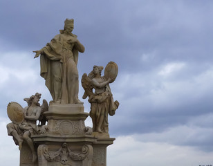 Fototapeta na wymiar 18th Century statue of St Francis Borgia & two angels. Charles Bridge, Prague. Moody clouded background.