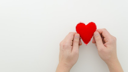 Fototapeta premium heart in man's hands. Felt Valentine heart in hands on a white background with copy space mock up