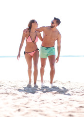 Young couple holding hands and walking on beach.