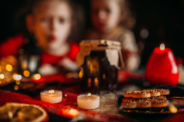 Children at the festive table. Bank of jam, candles and cookies on the table