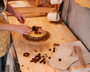 Chef decorates the cake with nuts and orange on the wood table