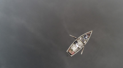 Aerial view about a very simple fishing boat on a cold autumn foggy morning near a beautiful...