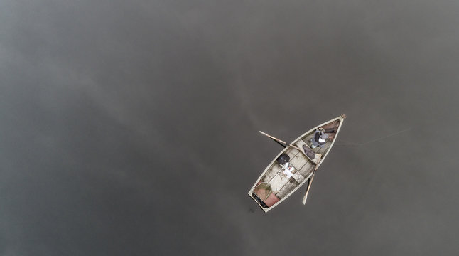 Aerial view about a very simple fishing boat on a cold autumn foggy morning near a beautiful fishing lake in Sic. Romania